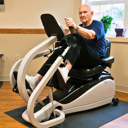 Man riding stationary bicycle-like machine for knee replacement rehabilitation.
