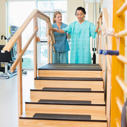 Image of male patient being helped up stairs during post-op rehabilitation.